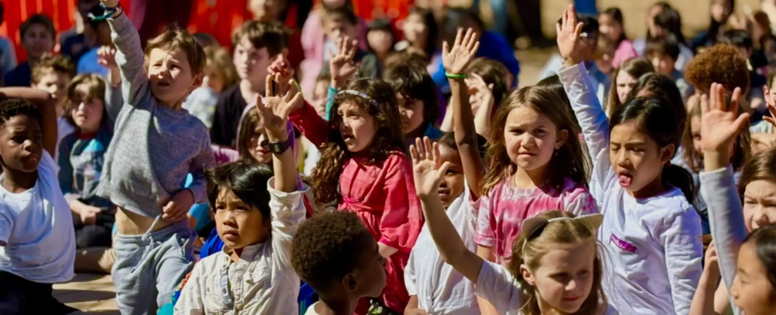 Students raising their hands outside